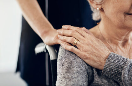 Femme âgée en fauteuil roulant tenant la main d'une personne