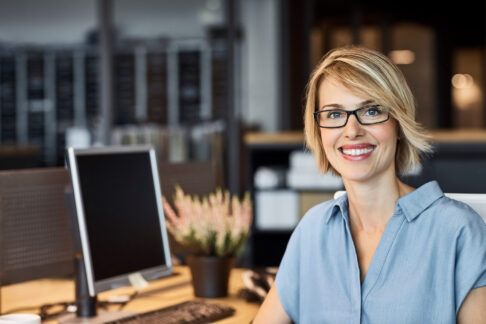 Femme souriante et confiante au bureau regardant droit vers l'objectif