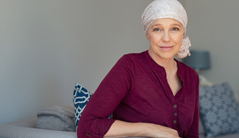 Une femme atteinte d'un cancer et portant un foulard regarde droit vers l'objectif de la camera