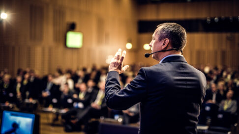 Un conférencier prend la parole devant une salle remplie en partageant un discours de motivation