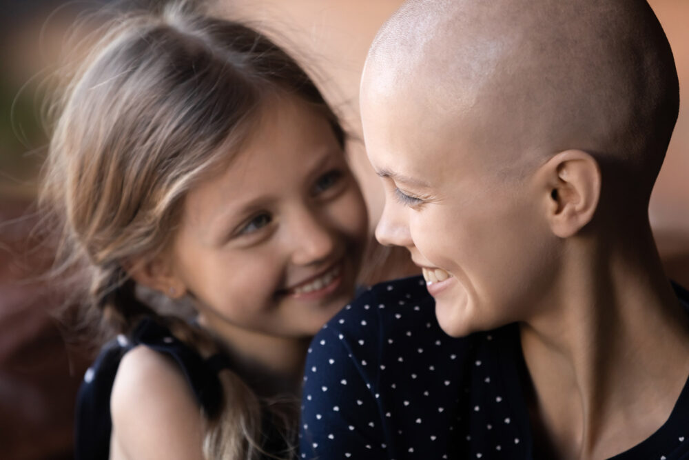 Une mère atteinte d'un cancer échange un regard complice avec sa petite fille et se sourient mutuellement